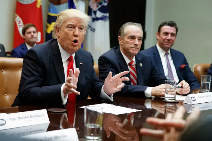 President Trump sits next to former Rep. Chris Collins and former Rep. Duncan Hunter, both later convicted of corruption charges, bur pardoned by Trump on Tuesday night.